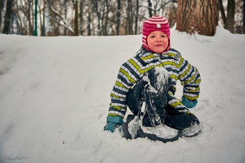 Free A Young Girl Sitting on the Snow Stock Photo