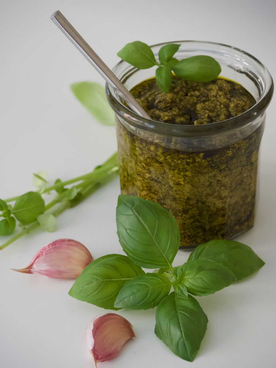 Open glass jar of green herb sauce with fresh basil and garlic — photo by thea a on Pexels