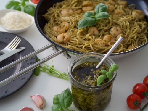 Free Savor the taste of shrimp pesto pasta garnished with fresh basil and cherry tomatoes. Stock Photo