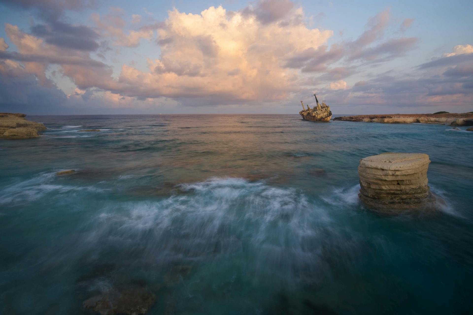 A stunning shipwreck off the coast of Cyprus against a vibrant sunset sky.
