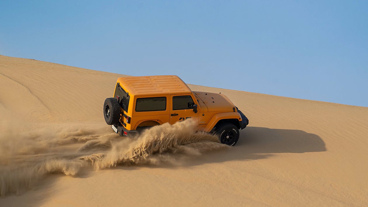 Free From above of modern vehicle driving through hot sandy dry desert in daytime Stock Photo