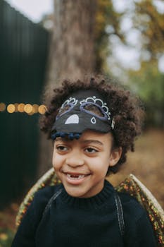 秋天，一个卷发男孩在户外戴着俏皮的口罩微笑