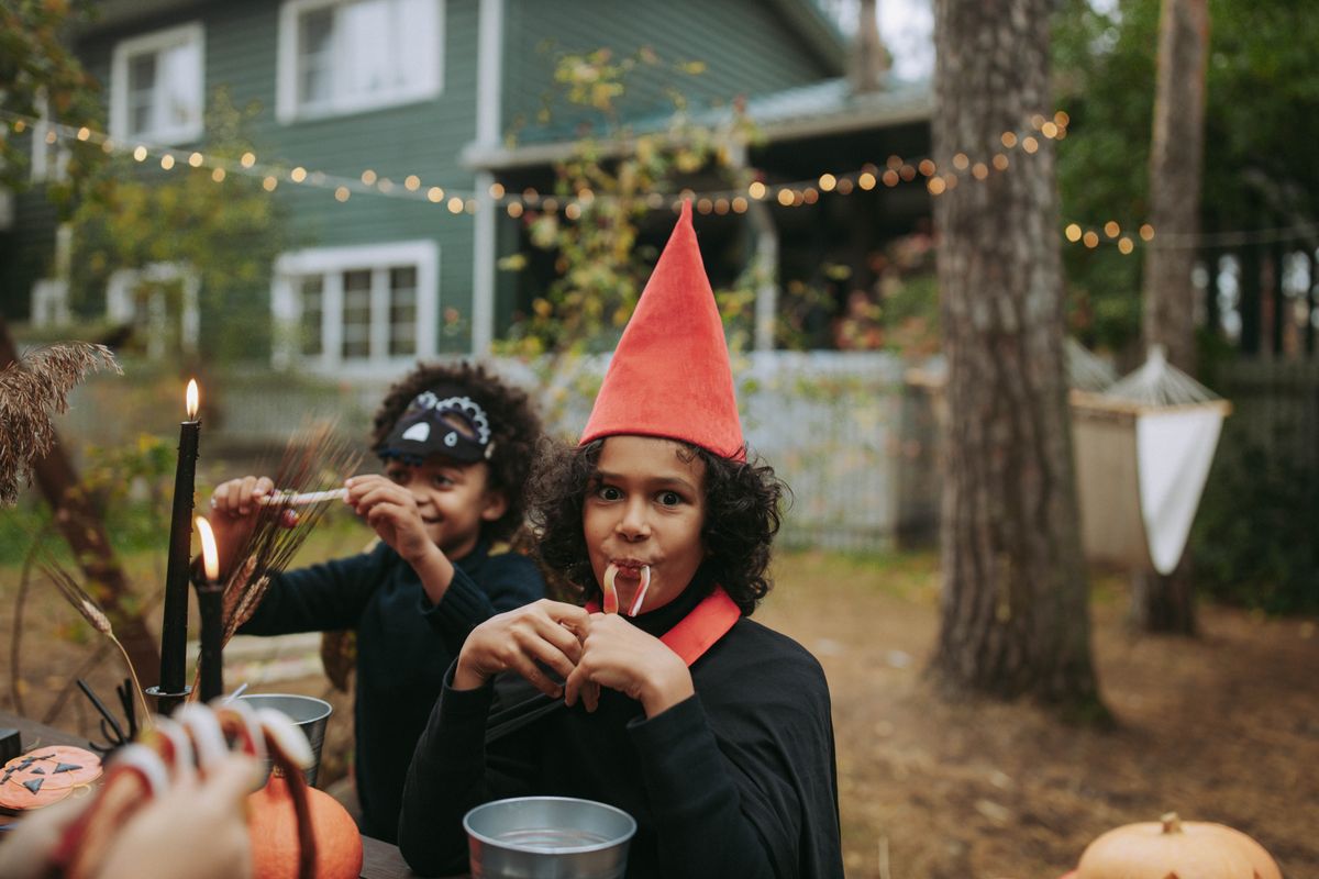 Children in costumes enjoying Halloween candy in a decorated backyard.
