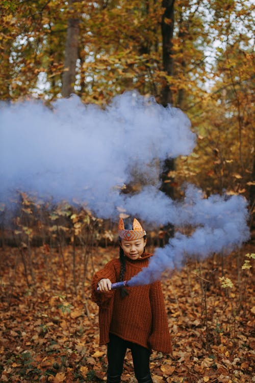 A Young Girl in Brown Knitted Sweater Holding a Smoke Bomb