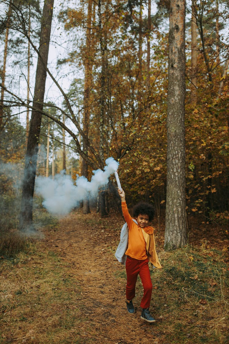 Kid With A Cape Running In A Forest While Holding A Smoke Bomb 