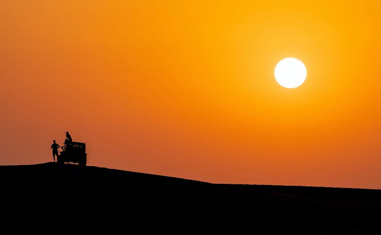 Silhouette Of A Couple And A Car At Sunset