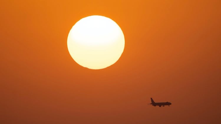 Airplane Flying In Sky At Sunset