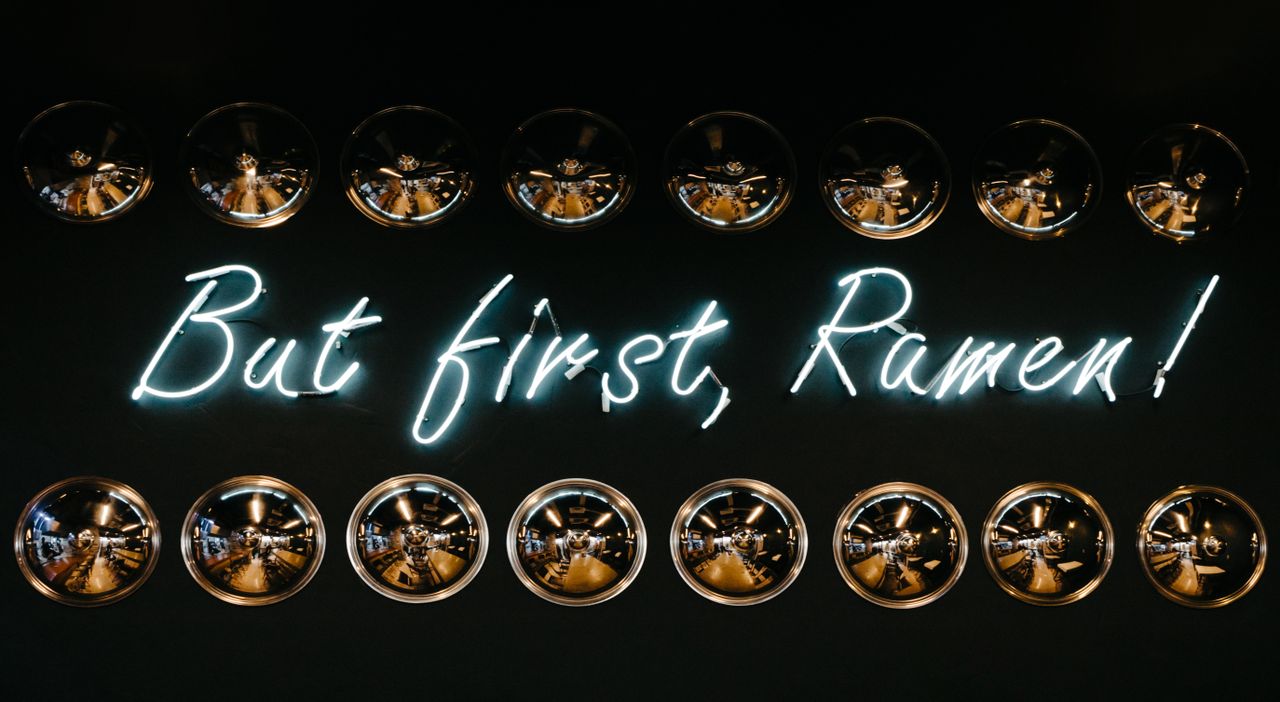 bright neon sign with reflection highlighting ramen with metallic hubc
