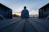 Man in Blue Dress Shirt Sitting on Gray Concrete Road