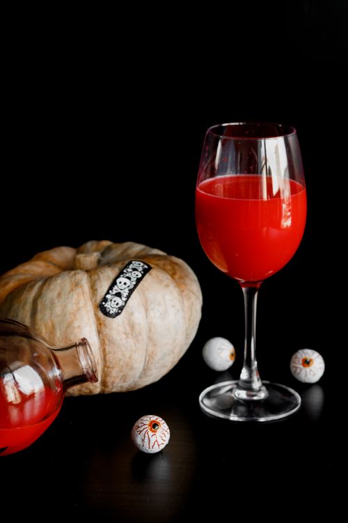 Free Spooky Halloween still life with a pumpkin, glass of red drink, and decorative eyeballs. Stock Photo