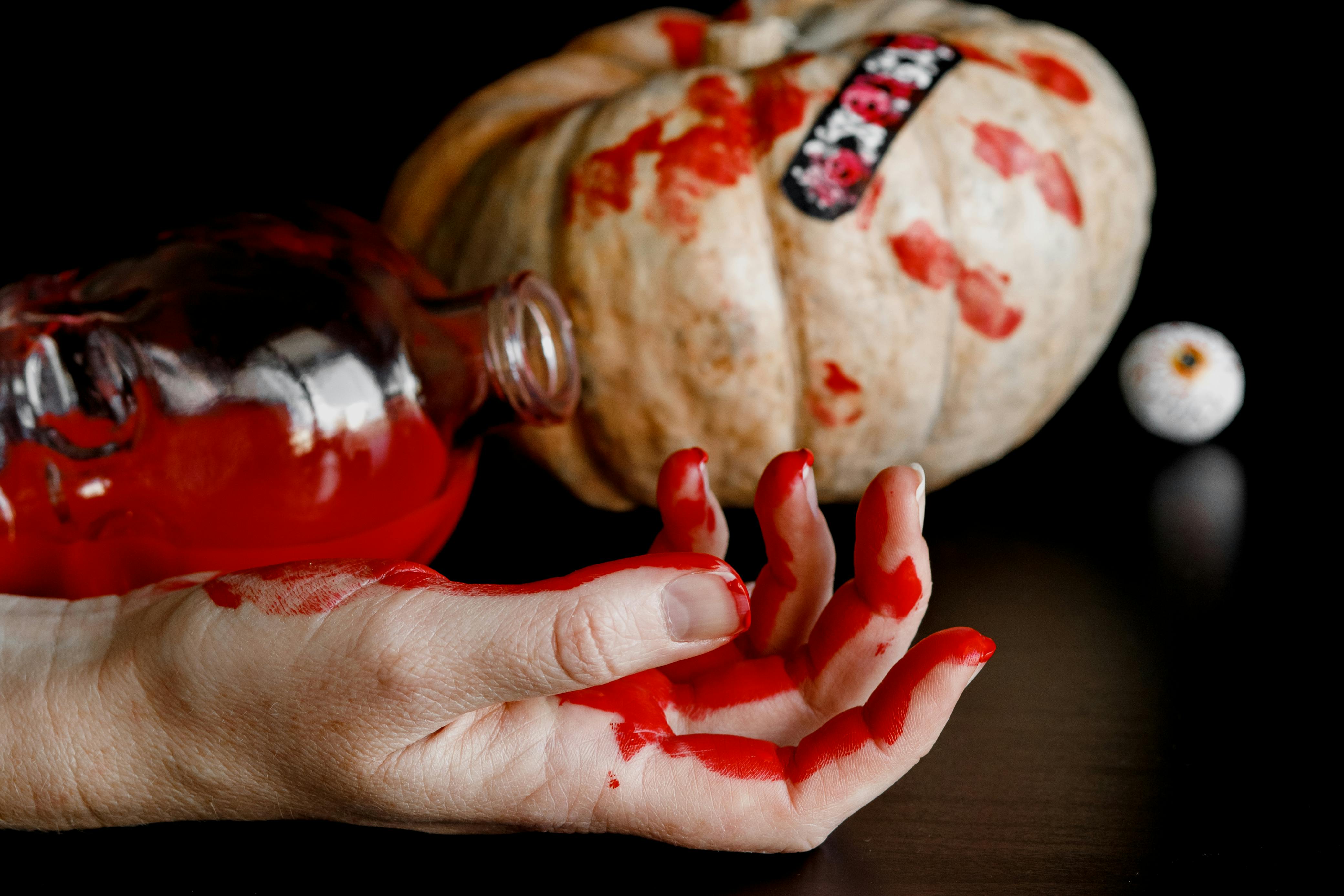 Close-up of a bloody hand with a pumpkin background, perfect for Halloween themes.