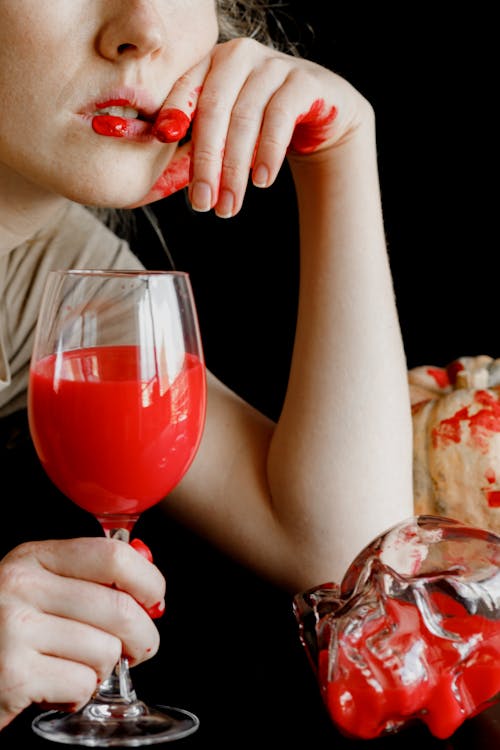 Free A Person with a Bloody Hand Holding a Glass of Red Liquid Stock Photo