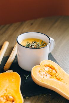 Close-up of creamy pumpkin soup with herbs in a rustic setting.