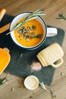 Warm and tasty homemade pumpkin soup garnished with seeds and rosemary in a cozy setting.