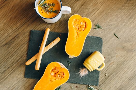 Delicious butternut squash soup with breadsticks on a rustic cutting board, perfect for fall cuisine.