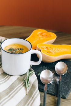 Warm butternut squash soup with rosemary garnish served in a cozy fall setting.