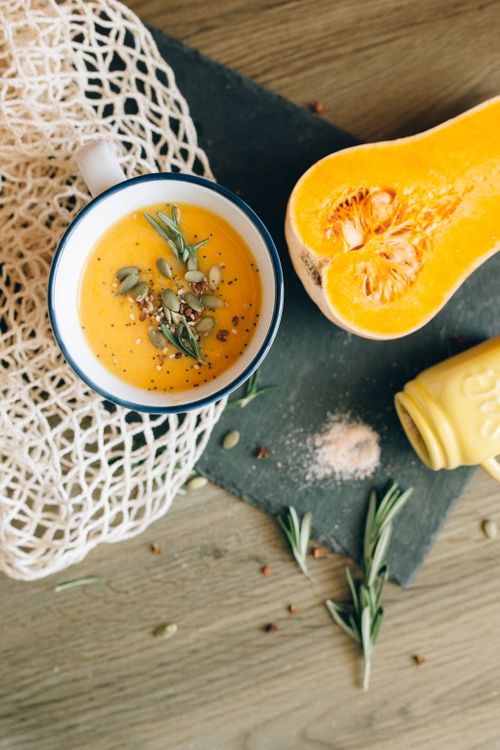 Free Delicious homemade butternut squash soup topped with pumpkin seeds and fresh herbs in a rustic setting. Stock Photo