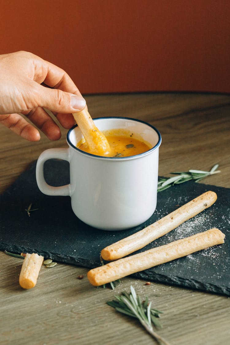 Person Dipping Cracker On Yellow Puree