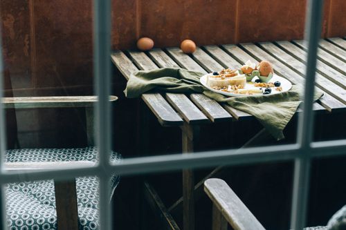 Free Cozy rustic breakfast with bread, cheese, and eggs on a wooden table as seen through a window. Stock Photo