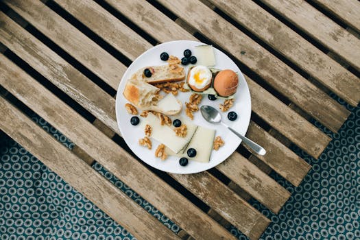 Overhead view of a rustic breakfast with cheese, boiled egg, and blueberries.