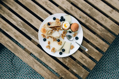 Free Overhead view of a rustic breakfast with cheese, boiled egg, and blueberries. Stock Photo