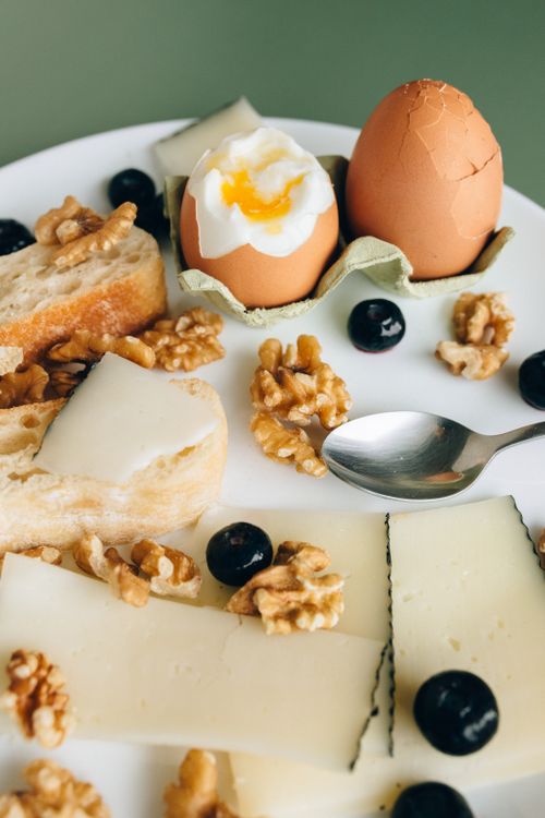 Free Delicious breakfast plate featuring boiled eggs, walnuts, cheese, and fresh bread. Stock Photo
