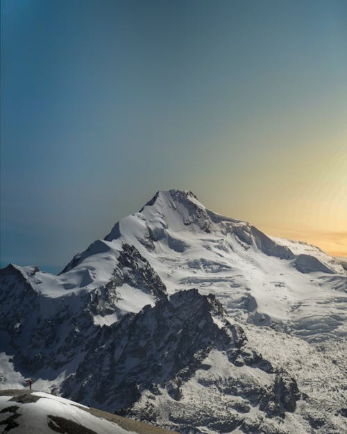 An Aerial Photography of  Snow Covered Mountain Under the Blue Sky