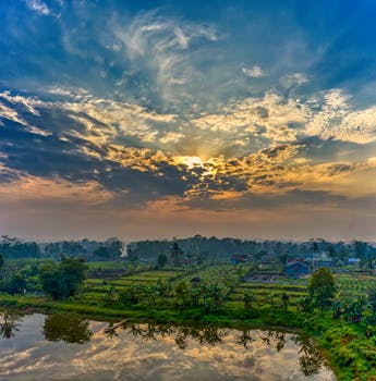 Beautiful sunrise over rural West Java with lush fields and dramatic clouds.