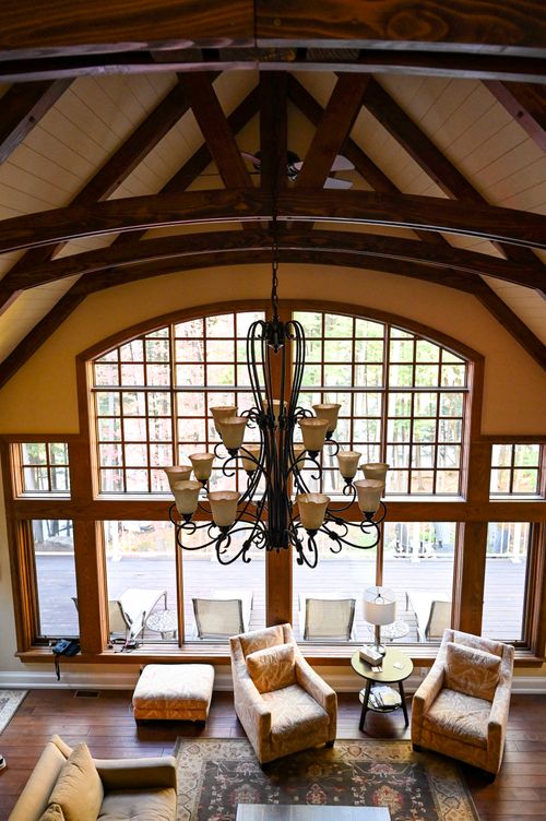 Free A stylish rustic living room featuring a grand chandelier and large windows. Stock Photo