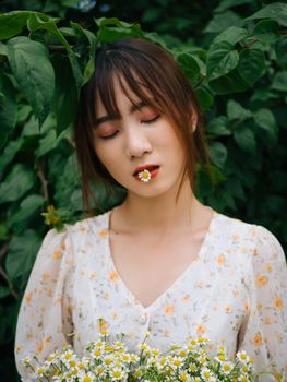 亚洲女性闭着眼睛，嘴唇上放着一束花