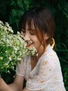 一位年轻女子闭着眼睛，在花园里微笑着享用新鲜的雏菊花束
