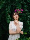 一位身着花卉连衣裙的优雅女子，在绿树成荫的花园里摆姿势