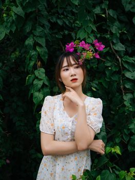 一位身着花卉连衣裙的优雅女子，在绿树成荫的花园里摆姿势