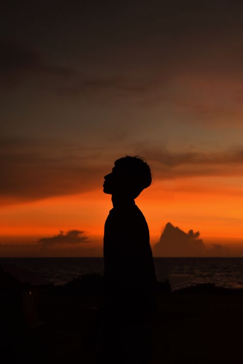 Free Silhouette of a person against a dramatic orange sunset on an Indian coastline. Stock Photo