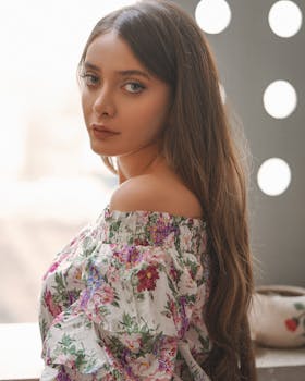 Elegant portrait of a woman with long hair in a floral blouse, captured with soft natural lighting.