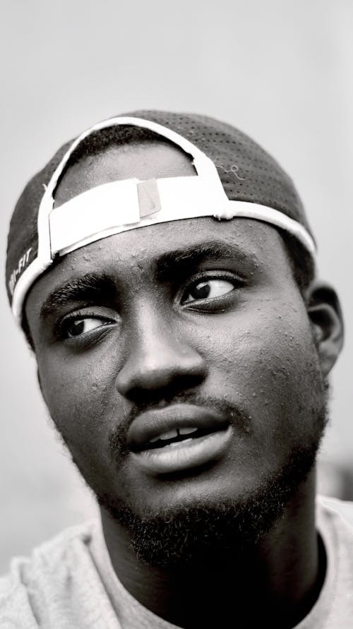 Black and white of African American male in cap thoughtfully looking away with mouth opened