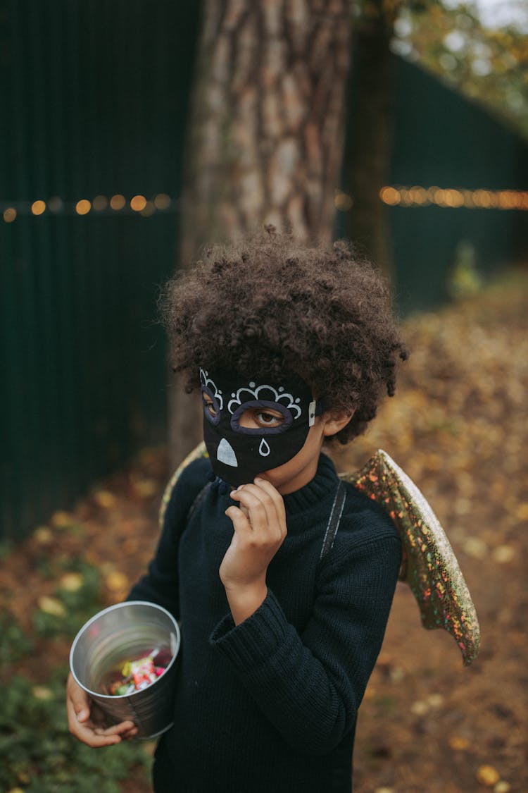 A Kid In Costume Wearing Mask Trick Or Treating During Halloween