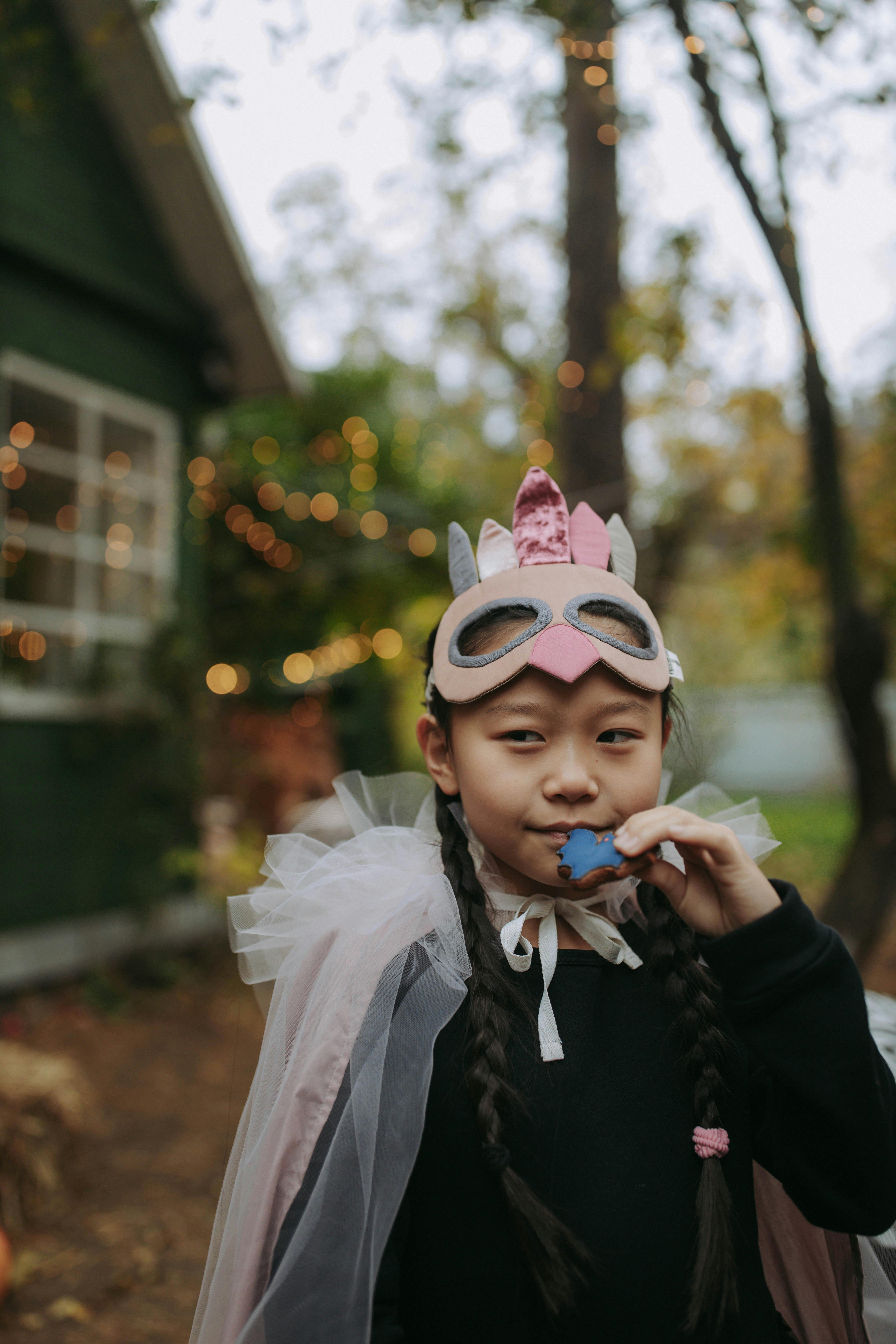 close up photo of a girl with pink sheer cape and masquerade mask