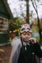 一个年轻女孩穿着戏服、戴着面具、披着斗篷，在户外享受秋日时光