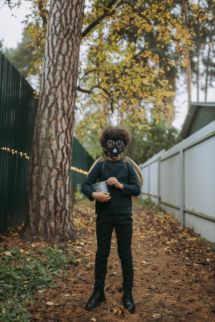 A Boy In Black Clothes And Black Mask Holding A Silver Bucket