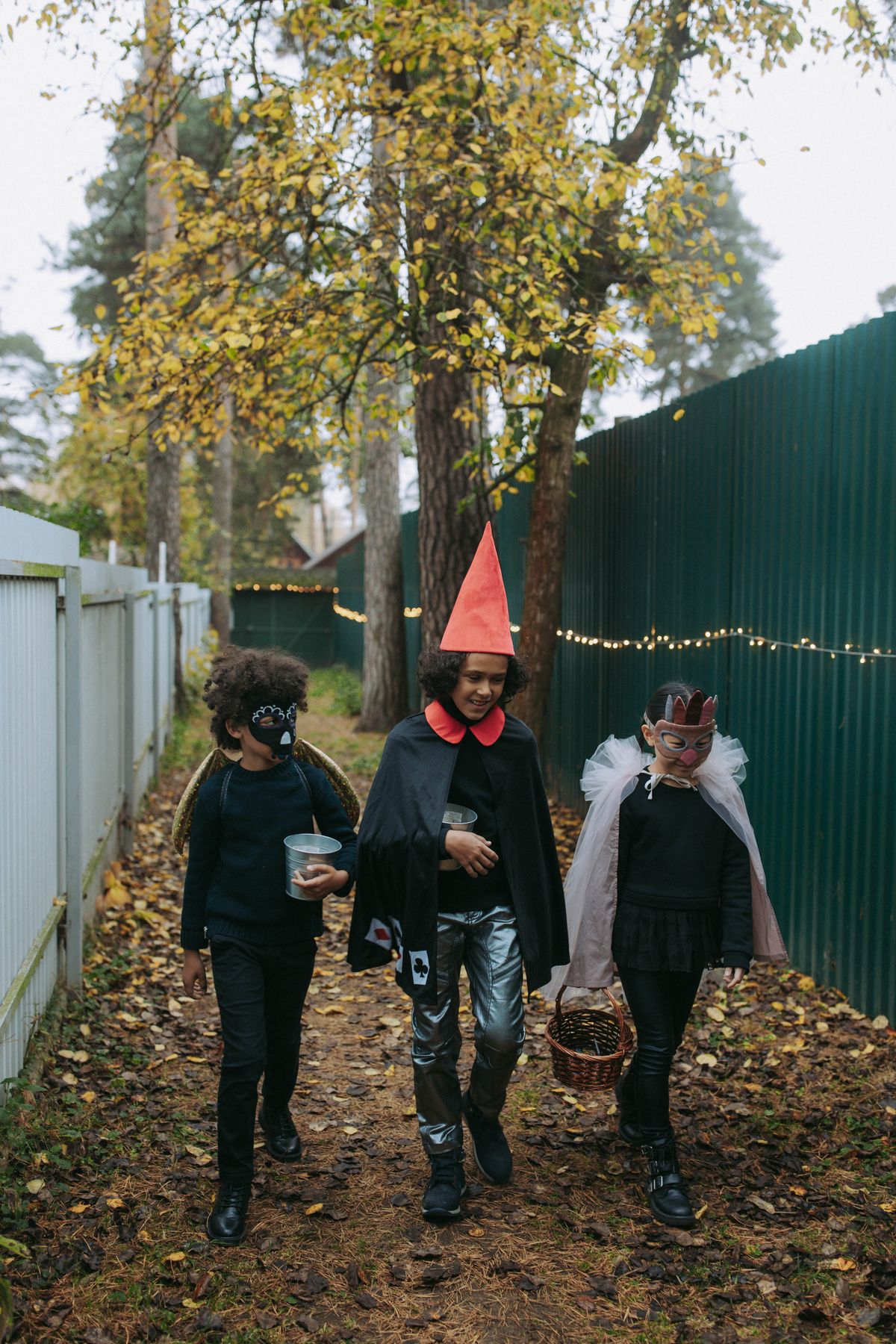 Children in Halloween costumes walking along an autumn path.