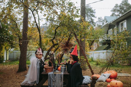 Free Kids in Halloween Costumes Eating in the Yard with Halloween Decorations Stock Photo