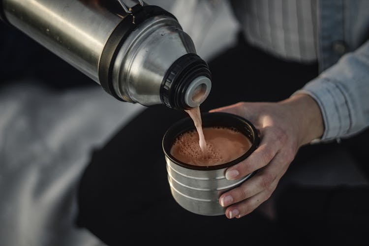 Woman Pouring Hot Coffee From Thermos Into Cup