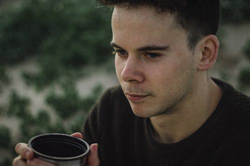 Calm brunette with cup of hot drink on nature