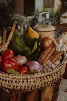 A rustic basket filled with fresh vegetables and spices on an outdoor market stand.