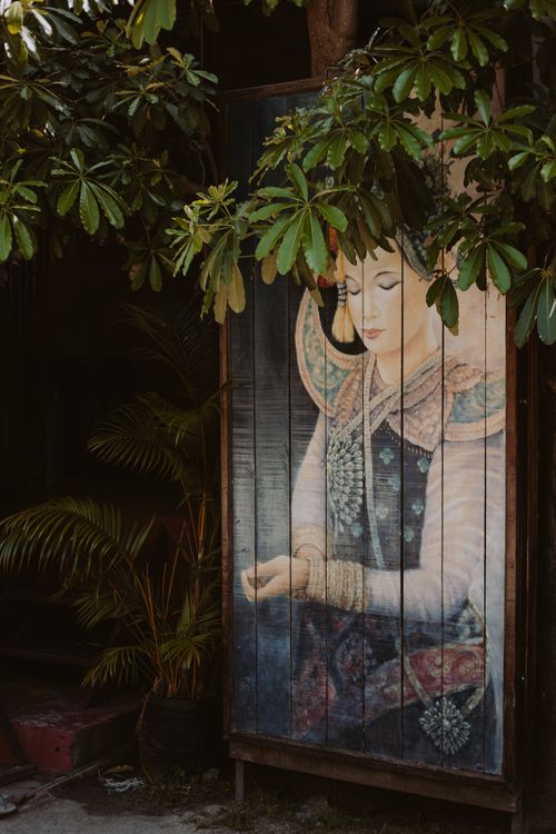 Free An elegant Asian-style painting hidden among lush garden foliage, depicting serenity. Stock Photo
