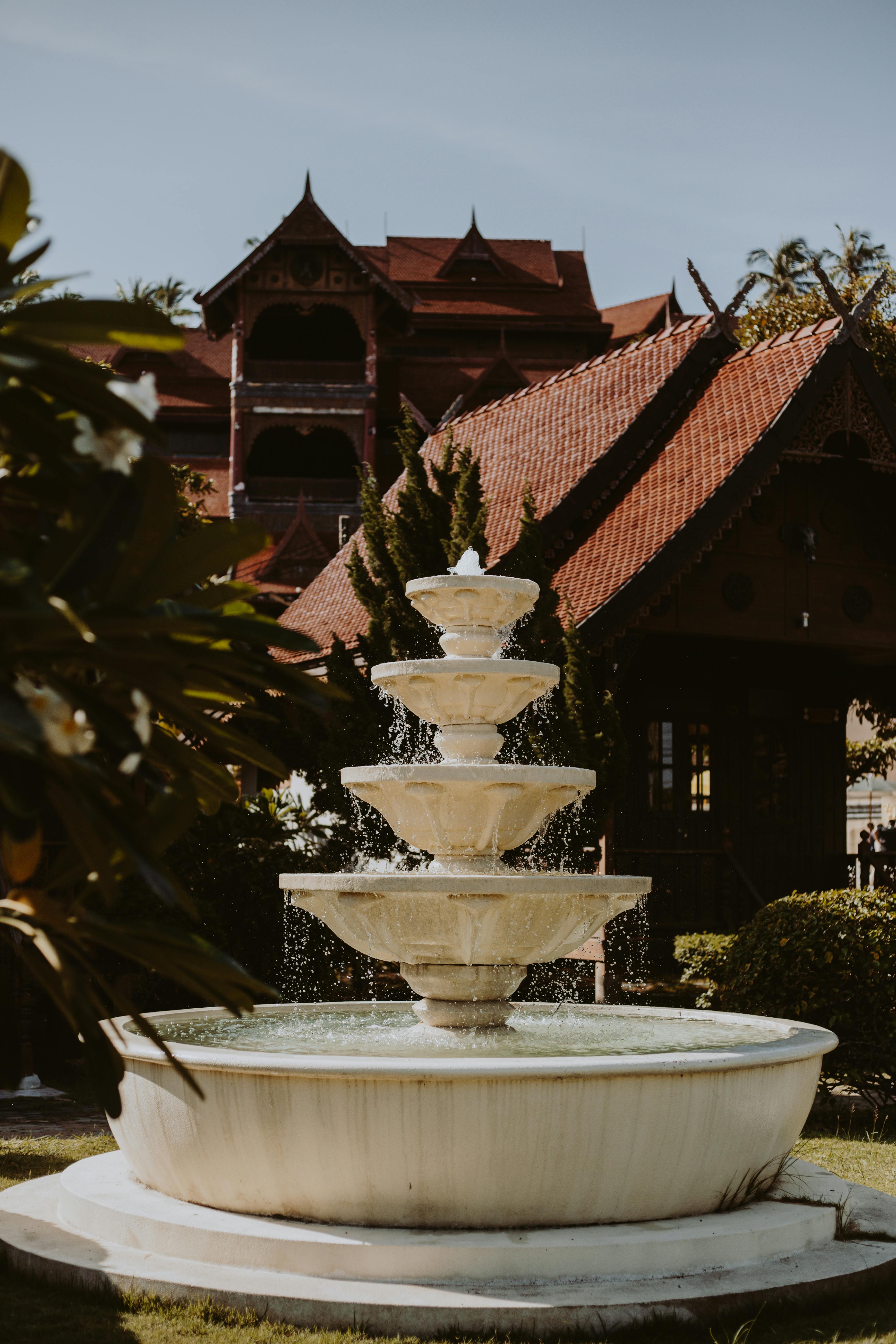 一座优雅的喷泉坐落在宁静的公园里，四周环绕着郁郁葱葱的绿植和古典建筑