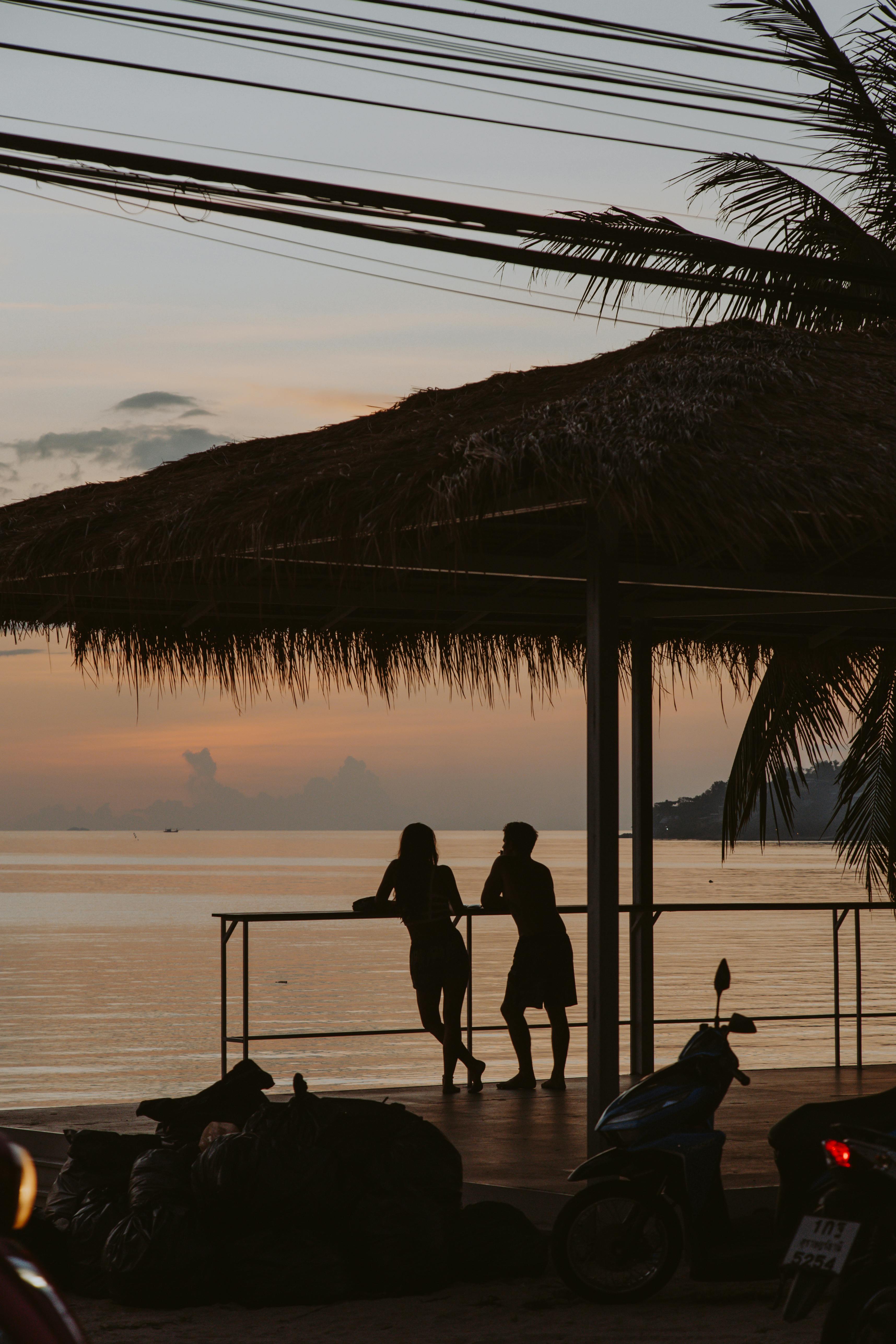 在宁静的海边日落映衬下，一对夫妇的剪影唤起浪漫与旅行的遐想
