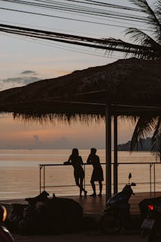 在宁静的海边日落映衬下，一对夫妇的剪影唤起浪漫与旅行的遐想