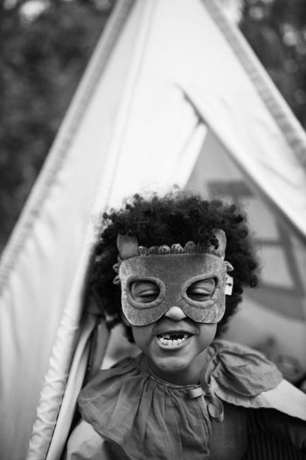 A child happily dressed in a Halloween costume, with a playful tent background.